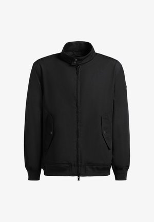 Zwarte jas met ritssluiting en opstaande kraag, klepzakken met drukknopen, geribbelde boorden aan mouwen en zoom, afgebeeld op een witte achtergrond.