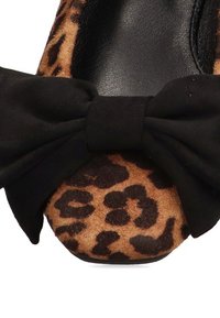 Zapato plano de estampado de leopardo con un lazo de gamuza negra, plantilla negra lisa y diseño de punta redondeada. Material superior texturizado.