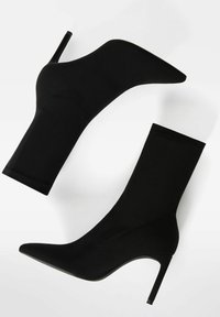 Czarne botki za kostkę z gładkiego, elastycznego materiału, w szpic, na wysokim obcasie w stylu stiletto, z minimalnym wykończeniem szwów i bez widocznych zapięć.