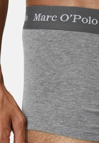 Boxer in cotone grigio con una texture morbida e un elastico grigio scuro con il nome del marchio "Marc O'Polo" in bianco.