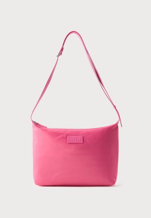 Sac à bandoulière rose avec une sangle réglable et une fermeture éclair visible, forme rectangulaire avec un patch logo cousu au centre avant.