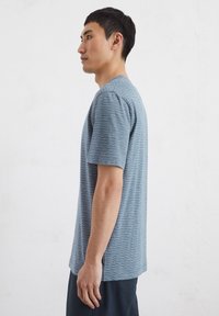Kurzarm-T-Shirt in Blau mit weißen horizontalen Streifen, Rundhalsausschnitt und lockerer Passform. Der Stoff wirkt glatt mit einer leichten Textur.