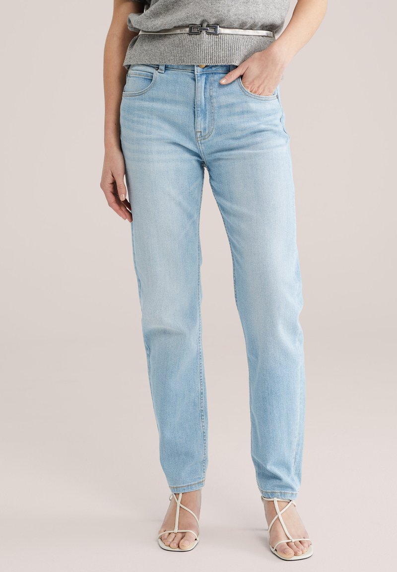 Svetlo modre denim hlače s pravim krojem, ki imajo pet žepov, zanke za pas in subtilno bledenje na nogah. Obute so s črtastimi sandali.