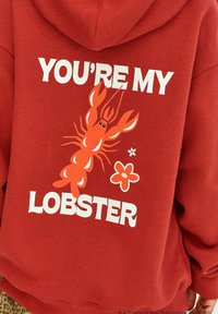 Červená mikina s kapucňou s grafikou homára a textom "TY SI MOJ HOMBÁR" v bielej farbe, s ďalšími kvetinovými akcentmi.