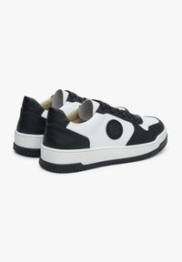 Černobílé tenisky s hladkou kůží, kulatou špičkou, kontrastními akcenty, plochými šňůrkami a texturovanou gumovou podrážkou. Vystouplý detail loga.