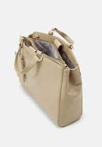 Borsa a mano sintetica beige con texture liscia, dotata di hardware color oro, chiusura con zip superiore e un ampio interno foderato in grigio.