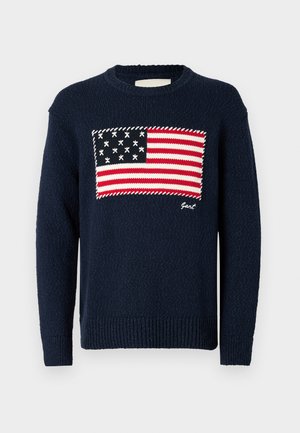 Marineblauwe gebreide trui met een ontwerp van de Amerikaanse vlag op de voorkant, met rode en witte strepen en witte sterren. Merkennaam "Gant" geborduurd daaronder.