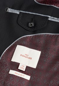 Intérieur de veste foncé avec doublure à motifs bordeaux, une poche noire boutonnée et des étiquettes portant la mention "Next Signature", taille "40R" et "Regular Fit".