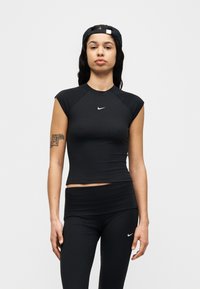 Μαύρο ριμπ αθλητικό τοπ με κοντά μανίκια και στρογγυλή λαιμόκοψη, συνδυασμένο με αντίστοιχα ψηλόμεσα κολάν, με λευκά λογότυπα Nike.