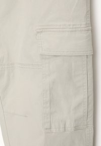 Ljusgrå cargobyxor i mjukt tyg har en sidoficka och synlig sömdetalj, med rak passform och slät textur.