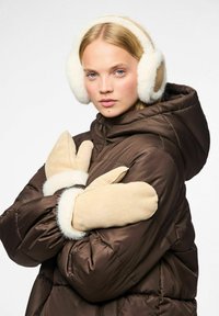Doudoune à capuche marron, associée à des mitaines beiges avec des poignets en fausse fourrure blanche et un bandeau assorti. Textures douces et couleurs chaudes.
