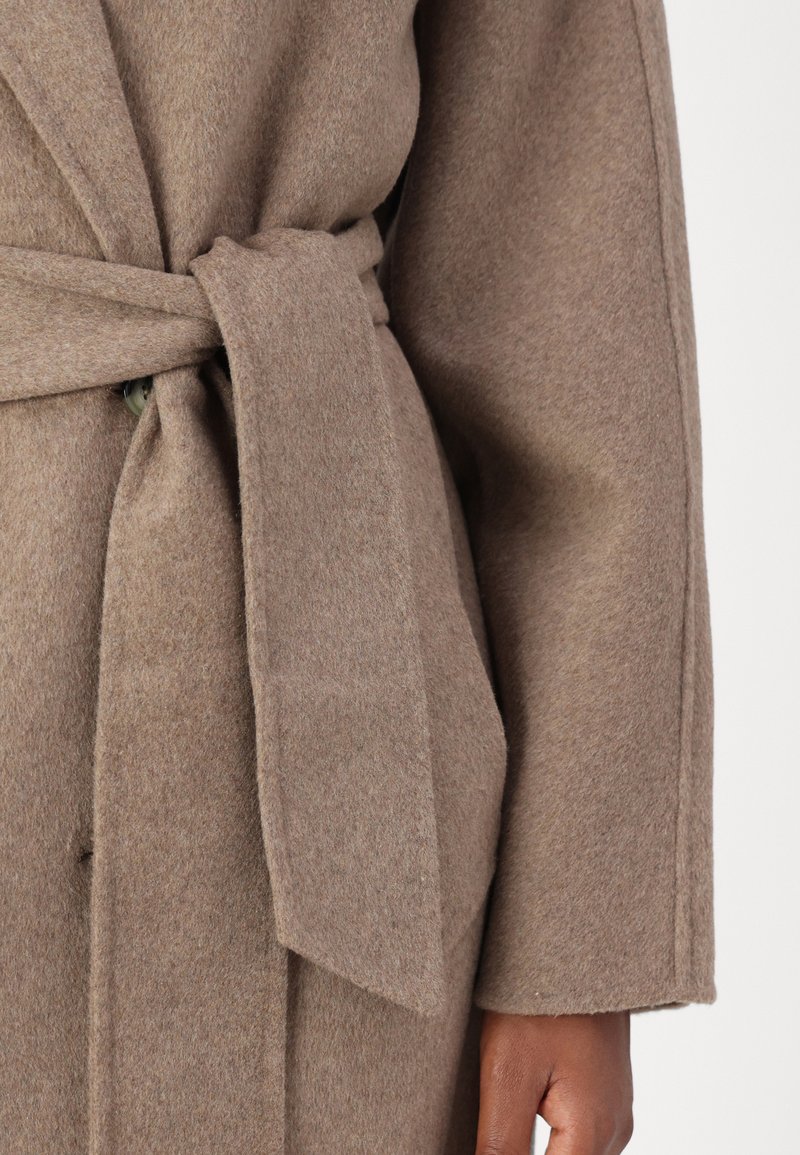 Brauner Wollmantel mit tailliertem Gürtel, aus einem strukturierten Stoff, mit breiten Revers und großen Seitentaschen.