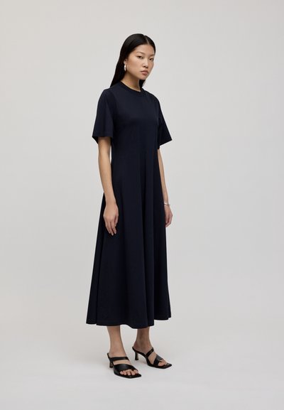 Granatowa midi sukienka z krótkimi rękawami i luźnym krojem. Wykonana z gładkiego materiału, ma okrągły dekolt i sięga kostek.