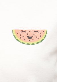 Φέτα καρπουζιού με χαμογελαστό πρόσωπο, κλειστά μάτια και γυαλιά σε σχήμα καρδιάς πάνω σε άσπρο υφασμάτινο φόντο.