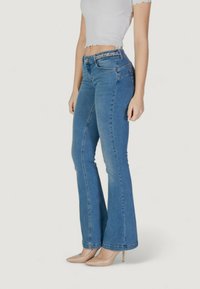 Jeans a campana di un blu chiaro, realizzati in denim, con vita media, sottili motivi in rilievo sulla cintura e una trama liscia.