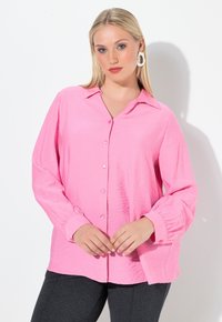 Rosa, knopflose Bluse aus strukturierter Stoff, mit übergroßen Ärmeln und Kragen. Verfügt über runde Knöpfe und einen lässigen Schnitt.