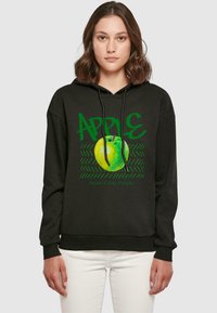Fekete kapucnis pulóver zöld "APPLE" felirattal és egy nagy zöld almás grafikával. A szöveg tartalmazza a "Édes. Friss. Egyszerű." kifejezést, eltérő stílusban.