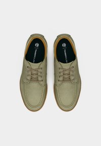 Πράσινα υφασμάτινα παπούτσια με δέσιμο κορδονιών, λάστιχο σόλας και καφέ λεπτομέρειες. Διαθέτουν ραμμένες λεπτομέρειες και επωνυμη εσωτερική σόλα.