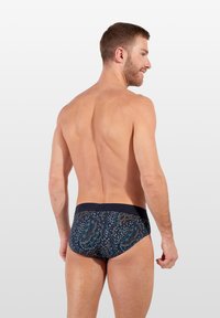 Marineblauwe zwembroek met een bedrukte ontwerp, met verschillende kleuren en een effen tailleband. De stof lijkt glad en aansluitend.