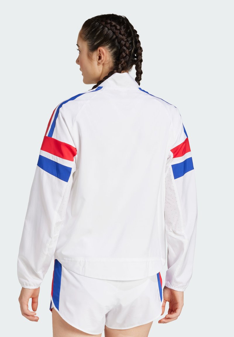 Chaqueta atlética blanca con franjas rojas y azules en las mangas, con cuello alto y paneles laterales perforados para transpirabilidad.