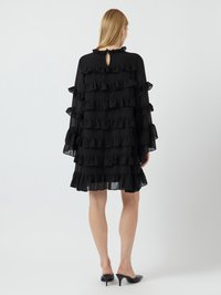 Μαύρο φόρεμα με στρώσεις και φουσκωτό σχέδιο, μακριά μανίκια και λεπτομέρεια με ανοιχτό πίσω μέρος, κατασκευασμένο από ελαφρύ ύφασμα με διάφανη υφή.