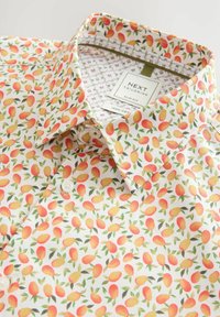Camisa de manga corta, ajustada, en algodón blanco con un colorido patrón de mangos y hojas. Presenta un cuello tipo button-down y una etiqueta de marca en el interior.