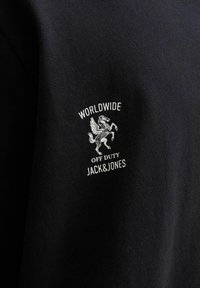 Schwarzes Stoff-T-Shirt mit einem weißen bestickten Logo mit einem Pferd und dem Text "WORLDWIDE OFF DUTY JACK&JONES." Klassische Passform und Struktur.