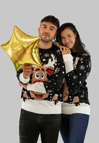 Schwarze Pullover mit weißen Manschetten zeigen ein Rentierdesign, Schneeflocken und ein verspieltes Farbschema. Eine Person hält einen goldenen Sternballon.