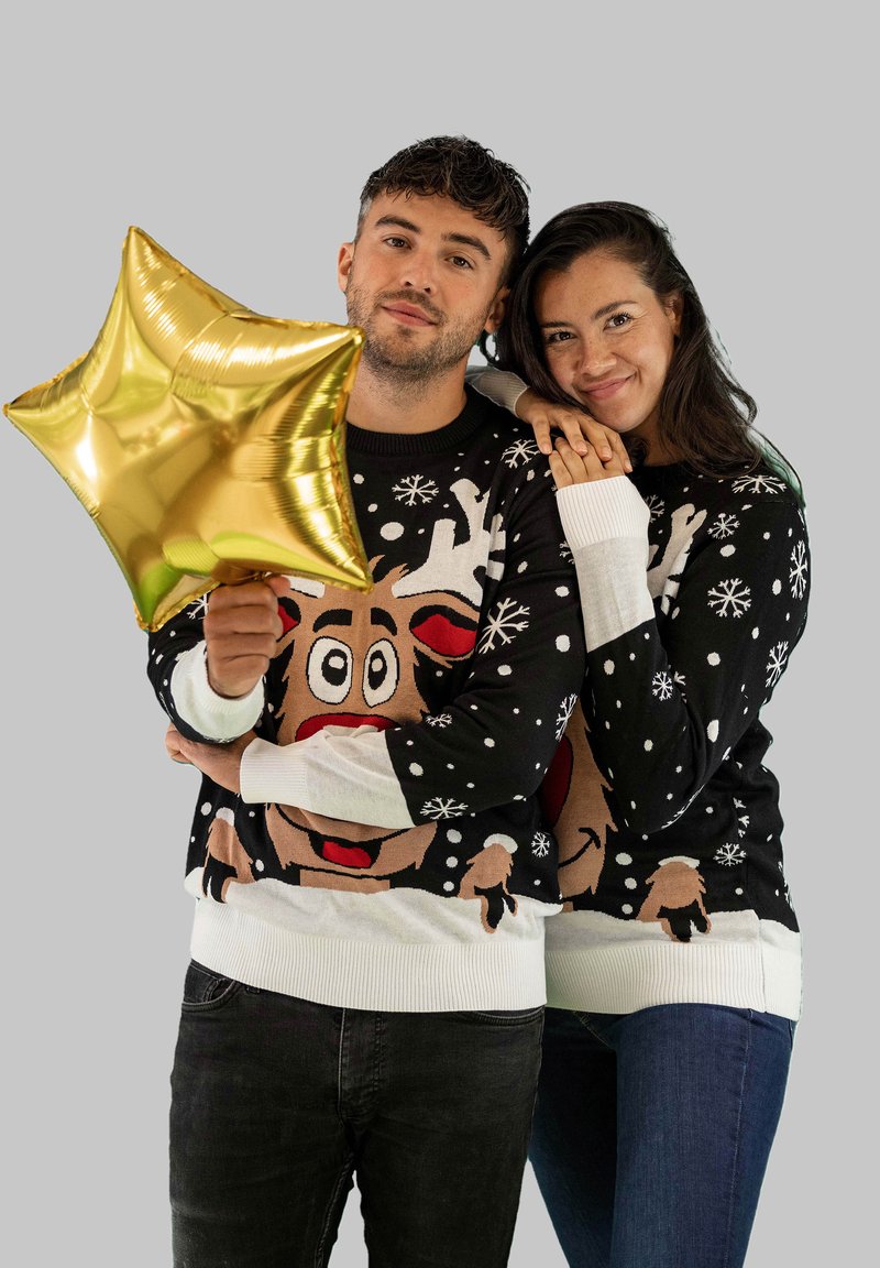 Schwarze Pullover mit weißen Manschetten zeigen ein Rentierdesign, Schneeflocken und ein verspieltes Farbschema. Eine Person hält einen goldenen Sternballon.