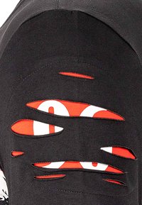 T-shirt nera con multiple sezioni ritagliate che rivelano un tessuto rosso a fantasia sottostante. Il design presenta un colletto rotondo e maniche corte.