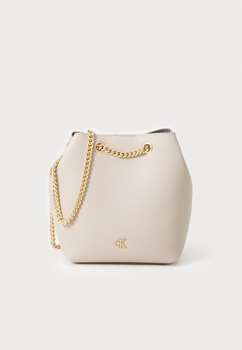 Lys beige læder spandtaske med en guldkæde-stropp, der har et minimalistisk design og præget logo på fronten.