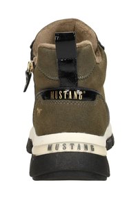 Braune Wildleder-Stiefelette mit einem glänzenden schwarzen Absatz und goldenem Logo. Mit Reißverschluss, texturierten Akzenten und einer weißen Gummisohle.