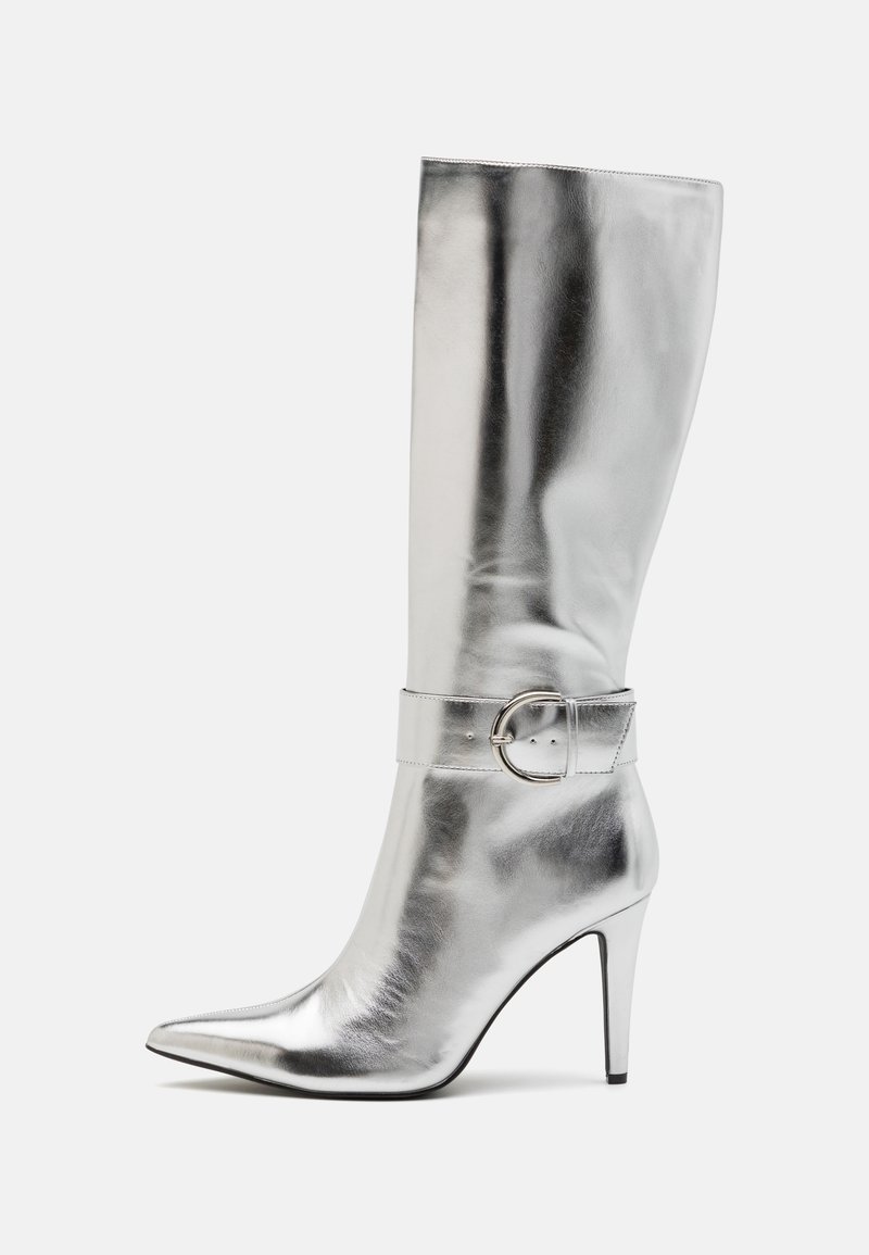 Stříbrná kozačka ke kolenům z jemné, lesklé kůže se špičatou špičkou a úzkým podpatkem. Má dekorativní páskový přezku kolem kotníku.