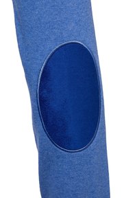 Tissu tricoté bleu avec une pièce ovale bleu plus foncé cousue dessus, montrant la texture et les détails des coutures sur une manche ou une jambe de pantalon.