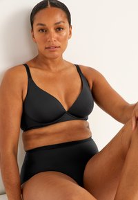 Musta alusvaatesetti, jossa on sileä kolmioelämäbralette, säädettävät hihnat ja korkeat saumatonta alaosaa. Pehmeä rakenne, ilman kuvioita.