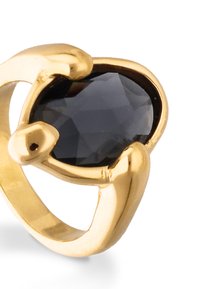 Anillo de oro con una gran piedra negra facetada, engastada en una banda abierta y esculpida. Acabado liso con brillo pulido.