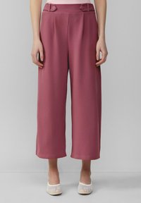 Pantalons à jambes larges dans une teinte rose, en tissu lisse avec un léger éclat, plis sur le devant et deux boutons décoratifs à la taille.