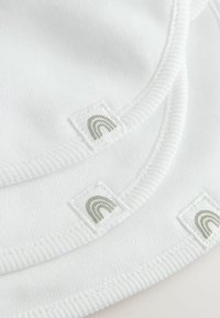 White fabric with ribbed texture featuring two square labels. Each label has a subtle gray rainbow design. Smooth, lightweight material.
