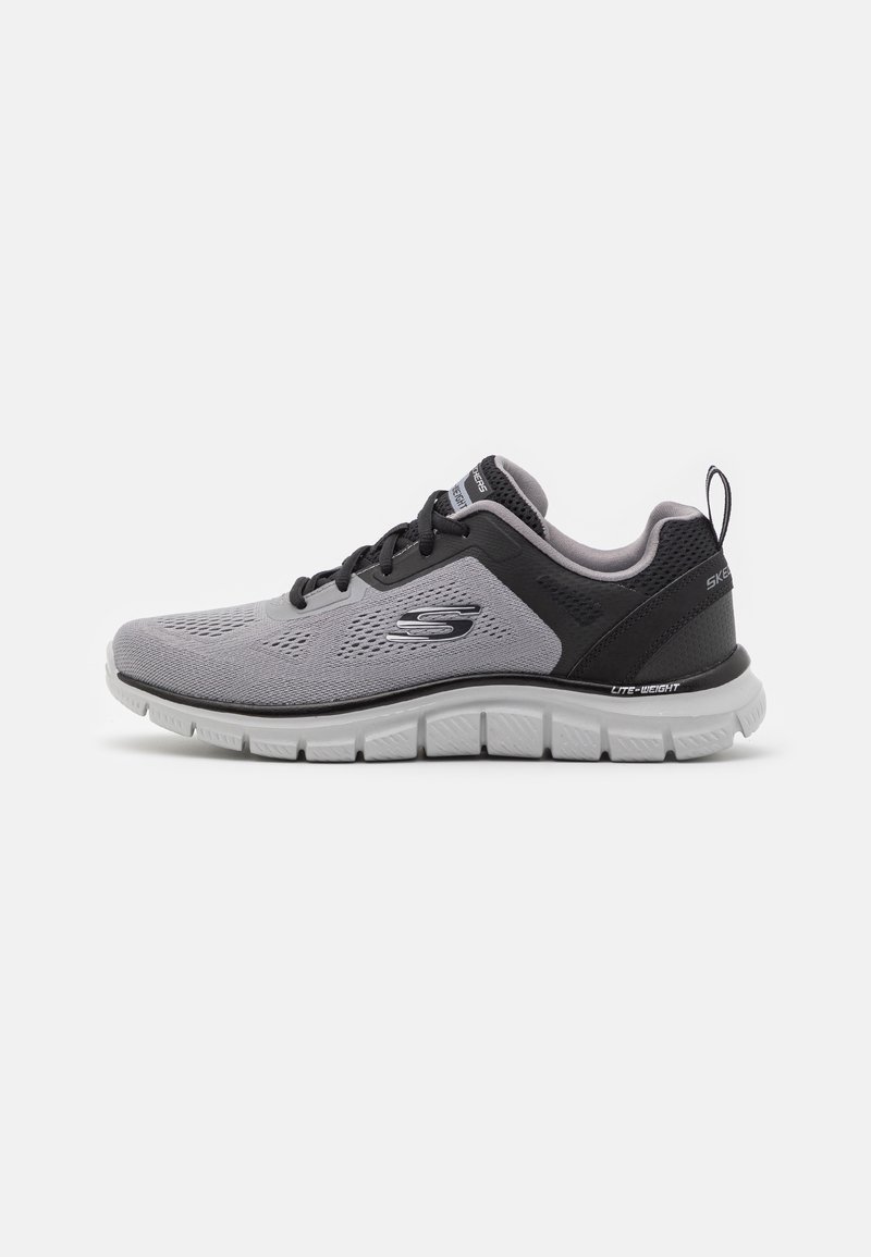 Graue Sportschuhe mit einem atmungsaktiven Obermaterial aus Mesh, schwarzen Akzenten und einer leichten weißen Sohle. Sie verfügen über runde Schnürsenkel und eine Zuglasche.