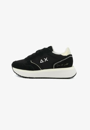 Czarno-biała niska tenisówka z grubą białą podeszwą, sznurowanym przodem, geometrycznym logo po boku oraz przeszyciami na pięcie.