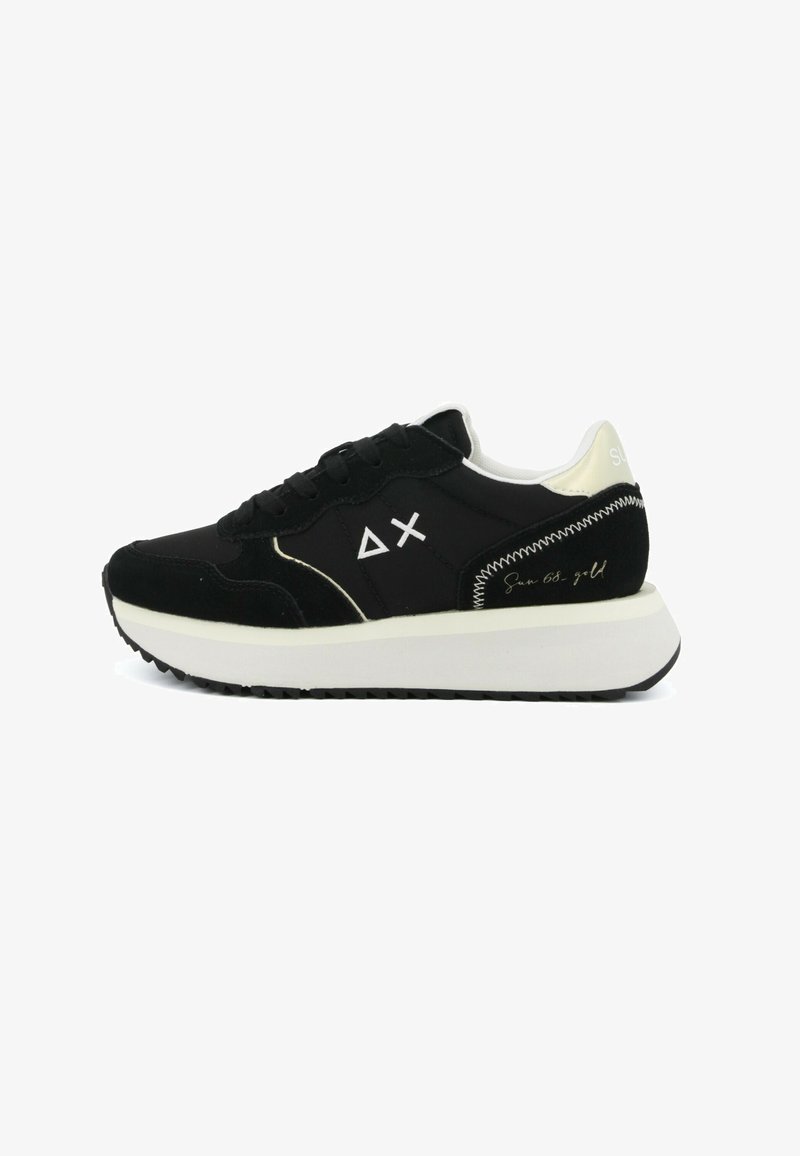 Scarpa da ginnastica bassa bianca e nera con suola bianca spessa, chiusura frontale con lacci, logo geometrico sul lato e dettagli cuciti sul tallone.