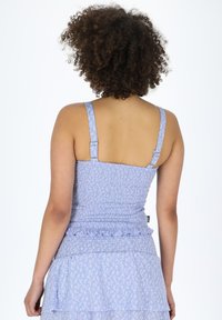 Top senza maniche azzurro chiaro con design arricciato, orlo fluttuo e motivo floreale; spalline regolabili con accenti metallici.