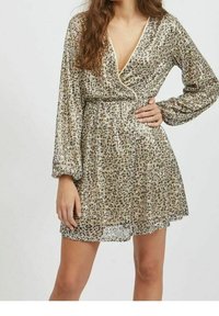 Glittrande guld wrap-klänning med långa ärmar, V-ringning, samlad midja och leopardmönster. Kort längd, slät textur och glänsande yta.