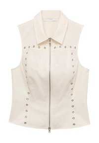 Top senza maniche color crema con zip frontale, collo ampio e dettagli in borchie metalliche lungo i lati. Tessuto liscio e design aderente.