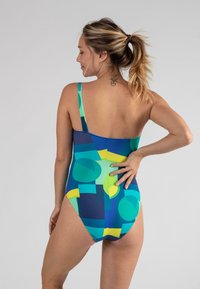 Eén stuk badpak in blauwe en groene geometrische patronen, met een lage rugontwerp en dunne schouderbanden. Glad stoftextuur.