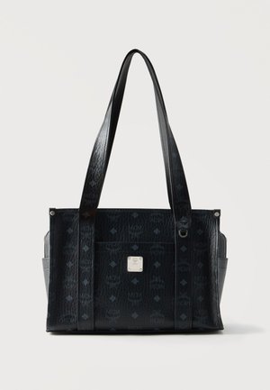 Sac cabas en cuir noir à surface texturée, deux longues poignées, poches latérales et une petite plaque métallique avec logo au centre devant.