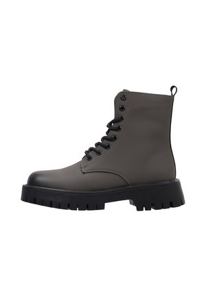 Bota de combate gris oscuro mate con cordones, suela gruesa negra con tacos y tira para tirar en la parte trasera, vista lateral sobre fondo blanco.