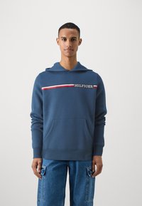 Sudadera azul de algodón, con un bolsillo frontal, puños acanalados y una franja horizontal con el texto "HILFIGER" en blanco.