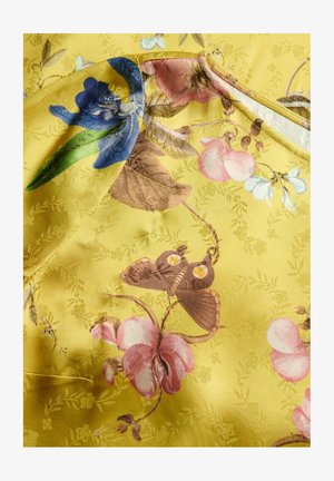 Floral fabric with a yellow background features blue orchids, pink flowers, and brown butterflies, showcasing intricate details and textures.