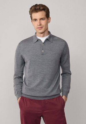 Pullover grigio a maglia con colletto, patta con due bottoni e maniche lunghe. Indossato con pantaloni bordeaux, caratterizzati da una trama liscia e un design semplice.